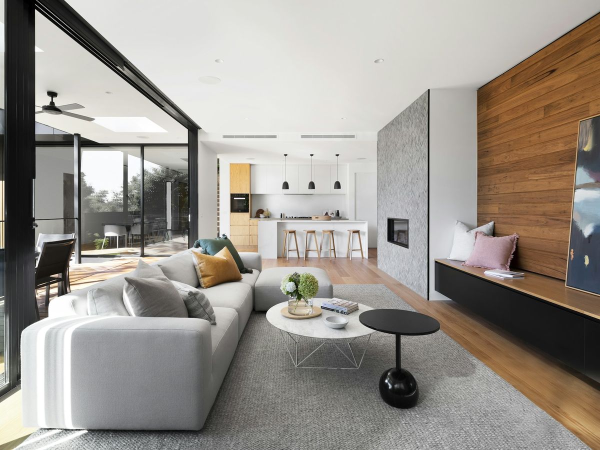 Open-plan living room with a timber feature wall, a pale sofa and the kitchen beyond