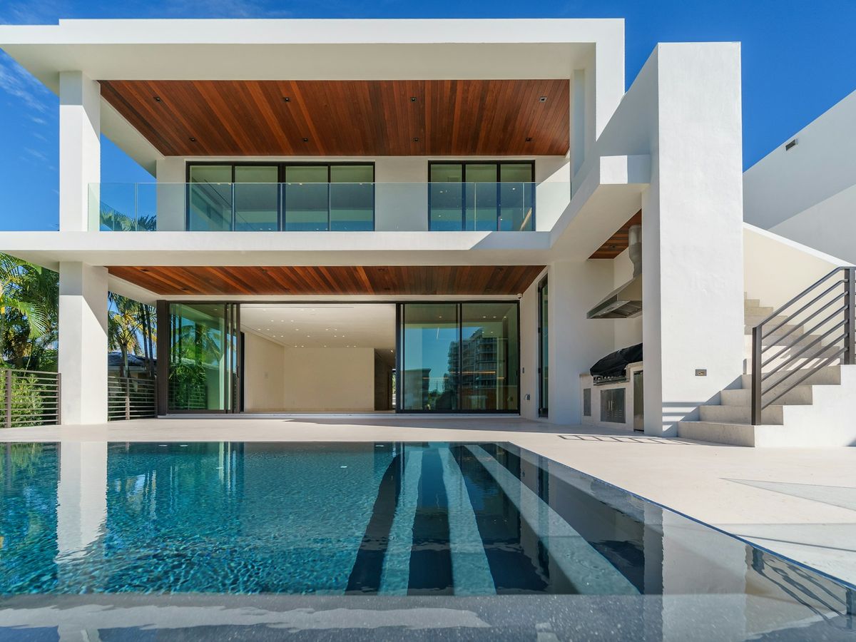 White two-storey modern villa with timber soffits and a long pool in front